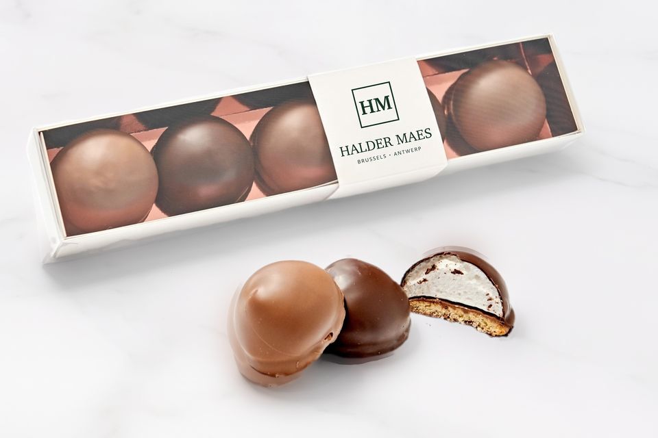 Doosje met vier chocolades en een sleeve met een bedrijfslogo, op marmer